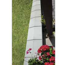 Detailní záběr zahradního ohraničení z betonových kamenů vedle trávníku a květin