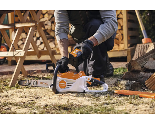 Pohled shora na osobu vkládající baterii do akumulátorové řetězové pily Stihl.