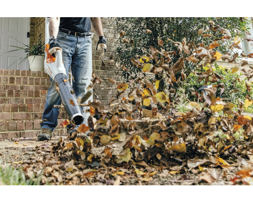 Osoba používá foukač listí k odstranění listí.