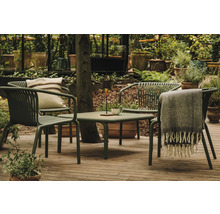 Zahradní scéna se stolem, židlemi, polštářem a dekou na terase obklopené rostlinami