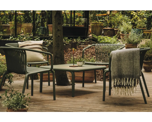 Zahradní scéna se stolem, židlemi, polštářem a dekou na terase obklopené rostlinami