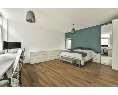 Světlá ložnice s pracovním prostorem, postelí, komodou a dřevěnou podlahou.