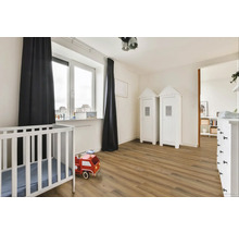 Světlý dětský pokoj s postýlkou, dřevěnou podlahou a dvěma bílými skříněmi ve stylu plážového domu.