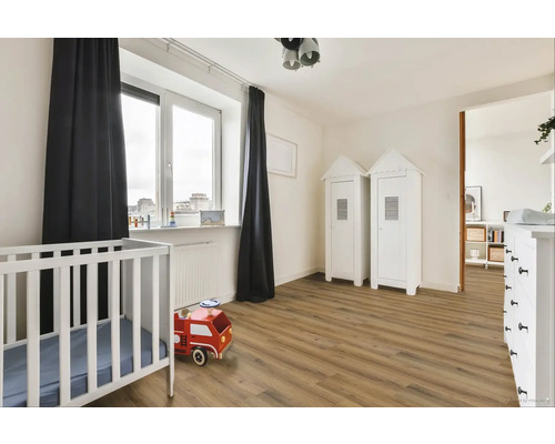 Světlý dětský pokoj s postýlkou, dřevěnou podlahou a dvěma bílými skříněmi ve stylu plážového domu.