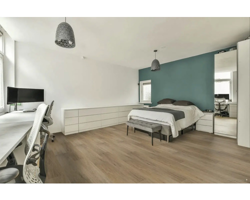 Světlá ložnice s pracovním prostorem, dvoulůžkem, komodou a dvěma závěsnými svítidly