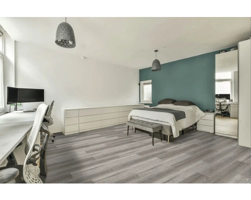 Světlá ložnice s pracovním prostorem, postelí, šedou podlahou a odpovídajícím osvětlením