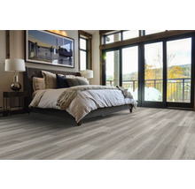 Ložnice s postelí, nočním stolkem, lampou a šedou dřevěnou podlahou