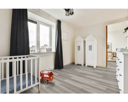 Světlý dětský pokoj s dětskou postýlkou, hračkou hasičským autem a skříněmi ve tvaru domu