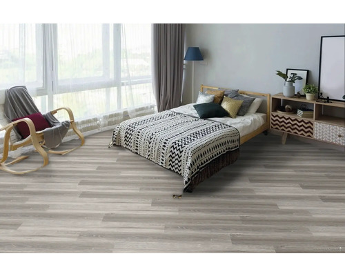 Ložnice s postelí, křeslem a světlou dřevěnou podlahou