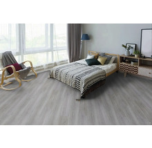 Světlá ložnice s dřevěnou postelí, vzorovanou denní dekou, dřevěným houpacím křeslem a komodou na podlaze