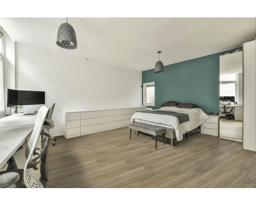 Světlá ložnice s postelí, psacím stolem a odpovídajícím nábytkem.