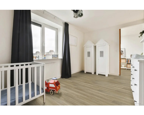 Světly dětský pokoj s dětskou postýlkou, hračkou hasičského auta a dvěma skříněmi ve stylu plážového domu