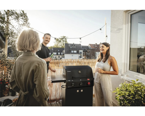 Scéna s plynovým grilem na balkoně, obklopená třemi mluvícími lidmi.