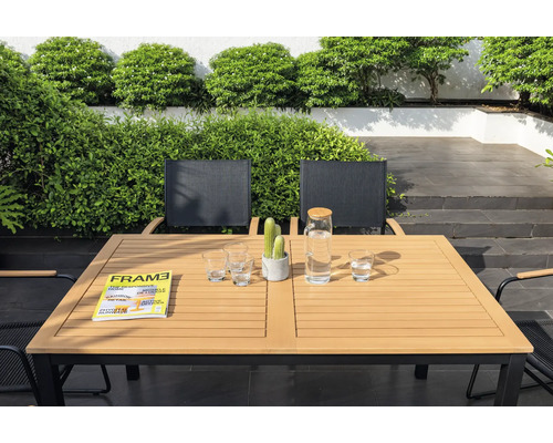 Zahradní scéna s jídelním stolem, židlemi, sklenicemi, karafou na vodu, časopisem a kaktusem