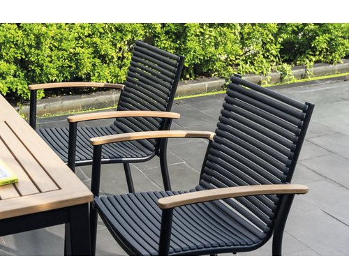 Dvě zahradní židle s dřevěnými područkami a černými kovovými rámy stojí vedle zahradního stolu.