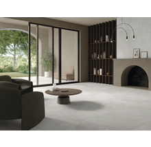 Světlý obývací pokoj s dlažbou, křeslem, konferenčním stolkem a regálem