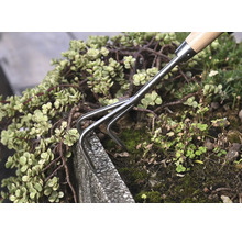 Ruční hrábě používané v zahradním záhonu