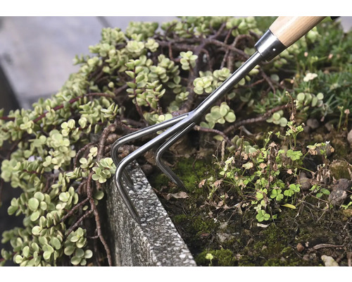 Ruční hrábě používané v zahradním záhonu