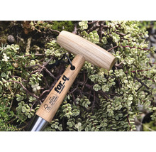 Zahradní nářadí s dřevěnou rukojetí a logem for-q, obklopené rostlinami