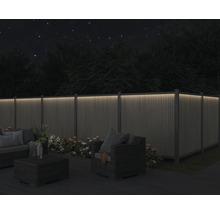 Zahrada s osvětleným plotem, posezením a květinami v noci