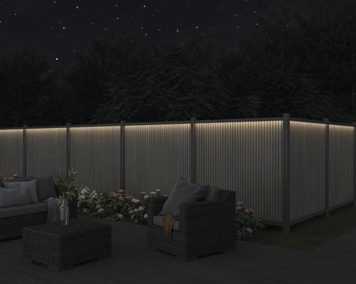 Zahrada s osvětleným plotem, posezením a květinami v noci