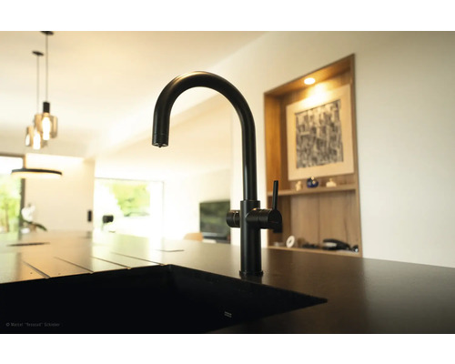 Černá kuchyňská baterie na dřezu v moderní kuchyni.