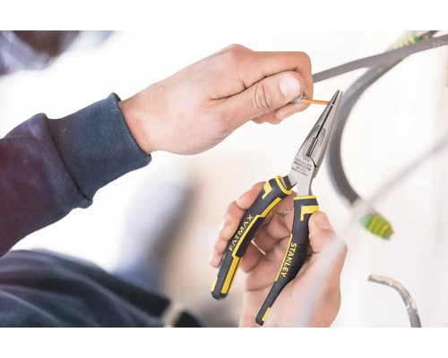 Ruce používají úzké kleště Stanley Fatmax ke svlékání kabelu.