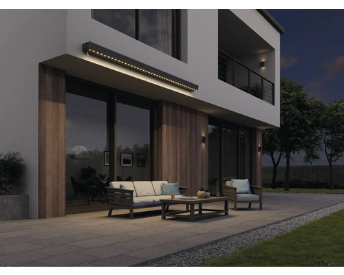 Moderní fasáda domu s osvětlenou markýzou, zahradním nábytkem a terasou