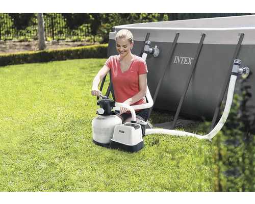 Žena obsluhuje pískovou filtraci Intex vedle bazénu