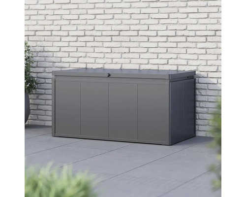 Šedý kovový úložný box před cihlovou zdí