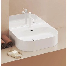 Moderní koupelna s bílým umyvadlem na desku, baterií a ručníky.