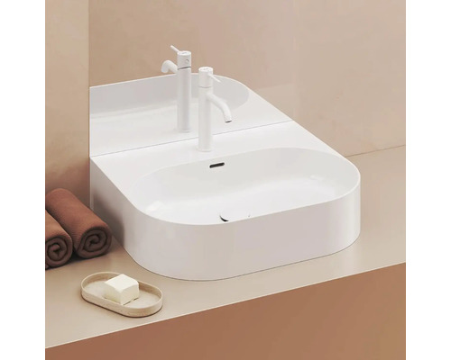 Moderní koupelna s bílým umyvadlem na desku, baterií a ručníky.