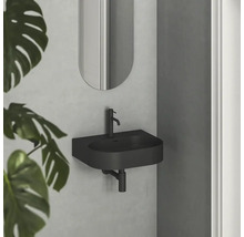 Černé umyvadlo se zrcadlem na stěně v koupelně