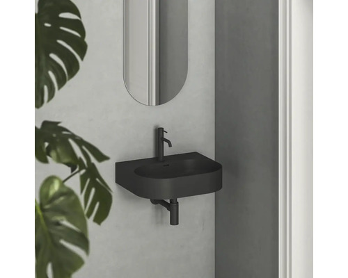 Černé umyvadlo se zrcadlem na stěně v koupelně