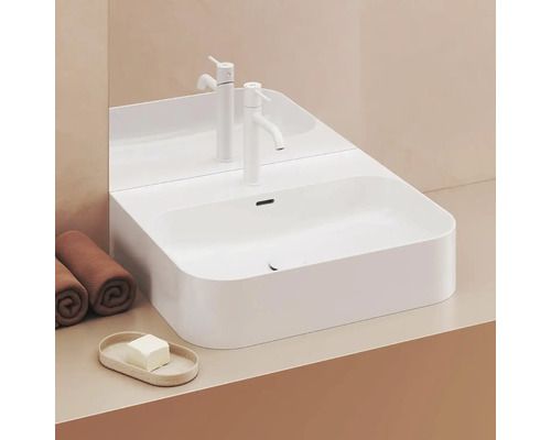 Bílé umyvadlo na desku s baterií, ručníky a mýdlem na umyvadlové skříňce