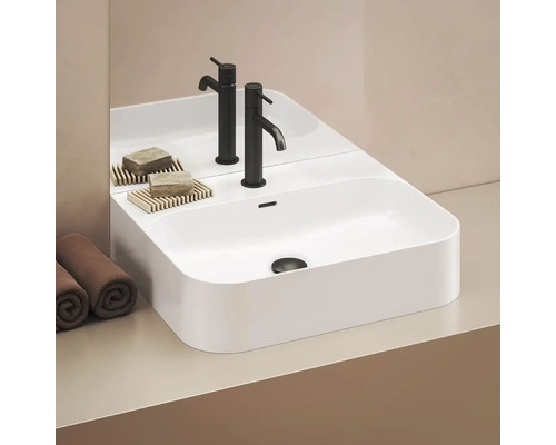 Moderní umyvadlo s bateriemi, mýdlem a ručníky v koupelně.