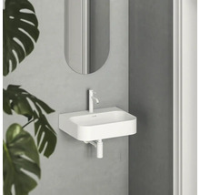 Bílé umyvadlo s baterií a zrcadlem ve světlé koupelně.