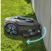 Robotická sekačka seká trávu podél zdi na trávníku