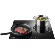 Indukční varná deska s steakem na pánvi a hrncem zeleniny