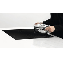 Indukční varná deska s osobou, která na ni pokládá hrnec