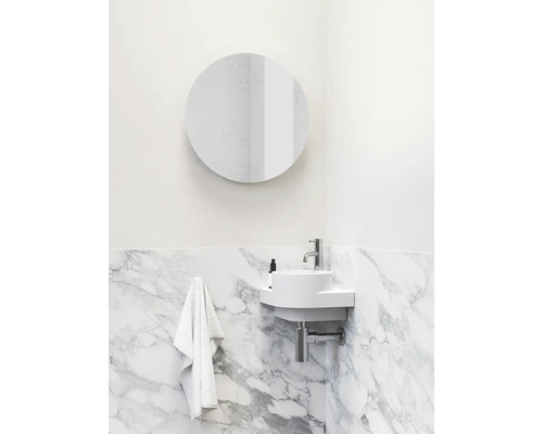 Koupelna s kulatým zrcadlem, umyvadlem a mramorovou stěnou