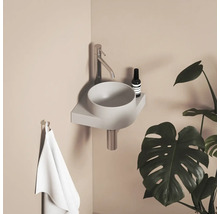 Moderní koupelna s umyvadlem na desku, baterií, ručníkem a pokojovou rostlinou.