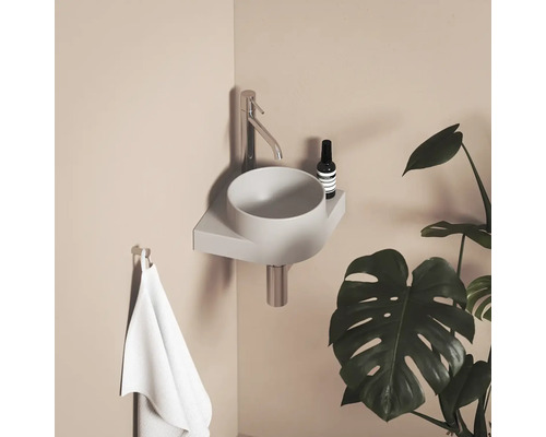 Moderní koupelna s umyvadlem na desku, baterií, ručníkem a pokojovou rostlinou.