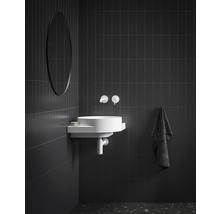 Koupelna s kulatým zrcadlem, umyvadlem, vodovodní baterií a ručníkem