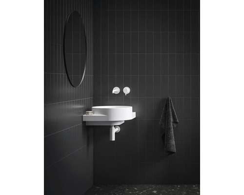 Koupelna s kulatým zrcadlem, umyvadlem, vodovodní baterií a ručníkem