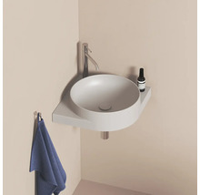 Kulaté umyvadlo s baterií, odkládací plochou a ručníkem v koupelně