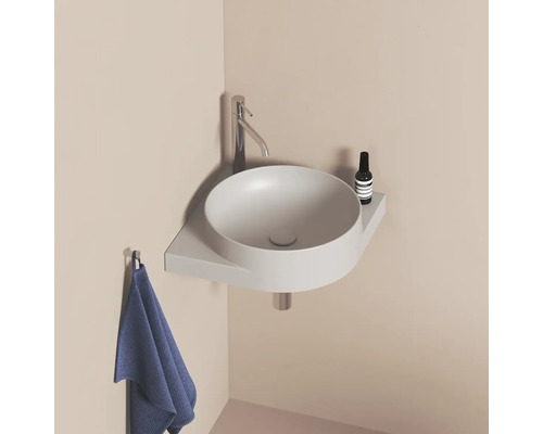 Kulaté umyvadlo s baterií, odkládací plochou a ručníkem v koupelně