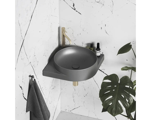 Šedé rohové umyvadlo s vodovodní baterií a ručníkem