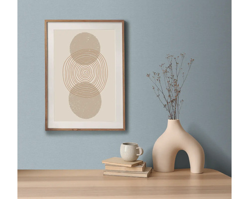 Dekorativní zátiší s uměleckým tiskem v rámu, knihami, šálkem a vázou na stole