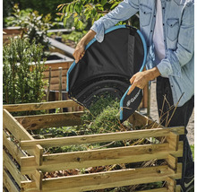Osoba vysypává pytel na listí Gardena do dřevěného uhelného koše na zahradě.